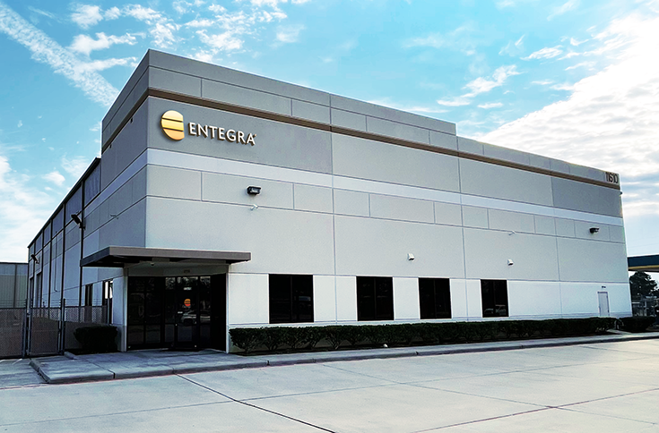 Photo of outside of new Entegra office in Houston, grey building with Entegra sign against blue sky.