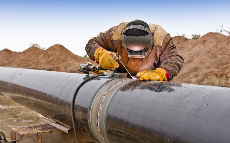 A welder adds a girth weld to a pipeline